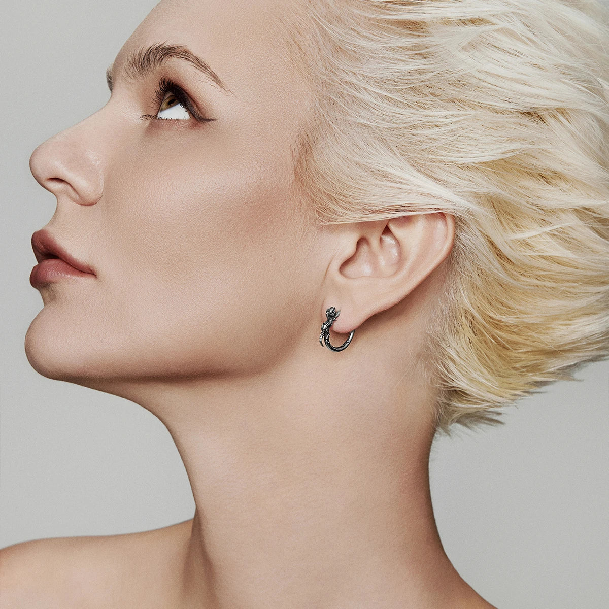 Model wearing a silver Dinosaur Legacy hoop earring with a small skeleton motif
