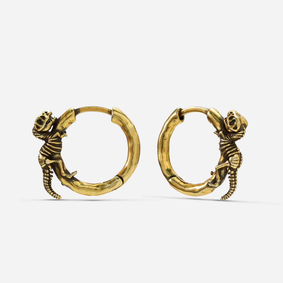 Pair of gold Dinosaur Legacy hoop earrings with curled dinosaur skeleton details