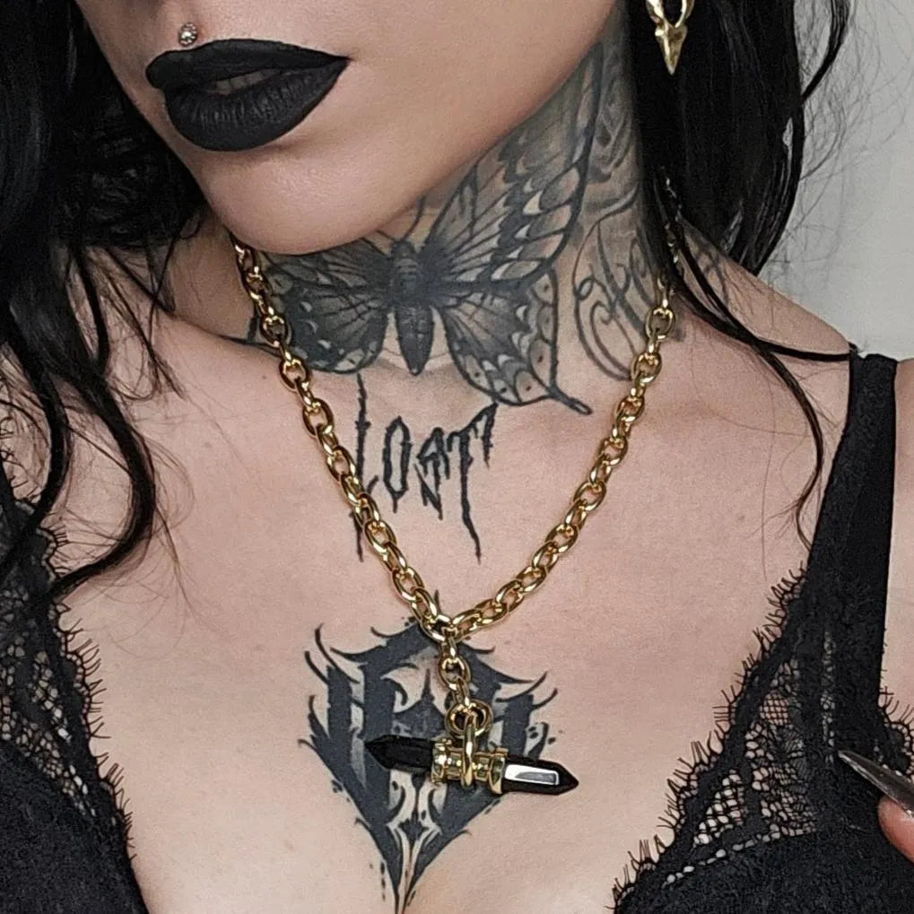 Model wearing the gold Dual Prism Necklace with a horizontal black crystal pendant, layered gothic jewelry, and dark alternative styling.