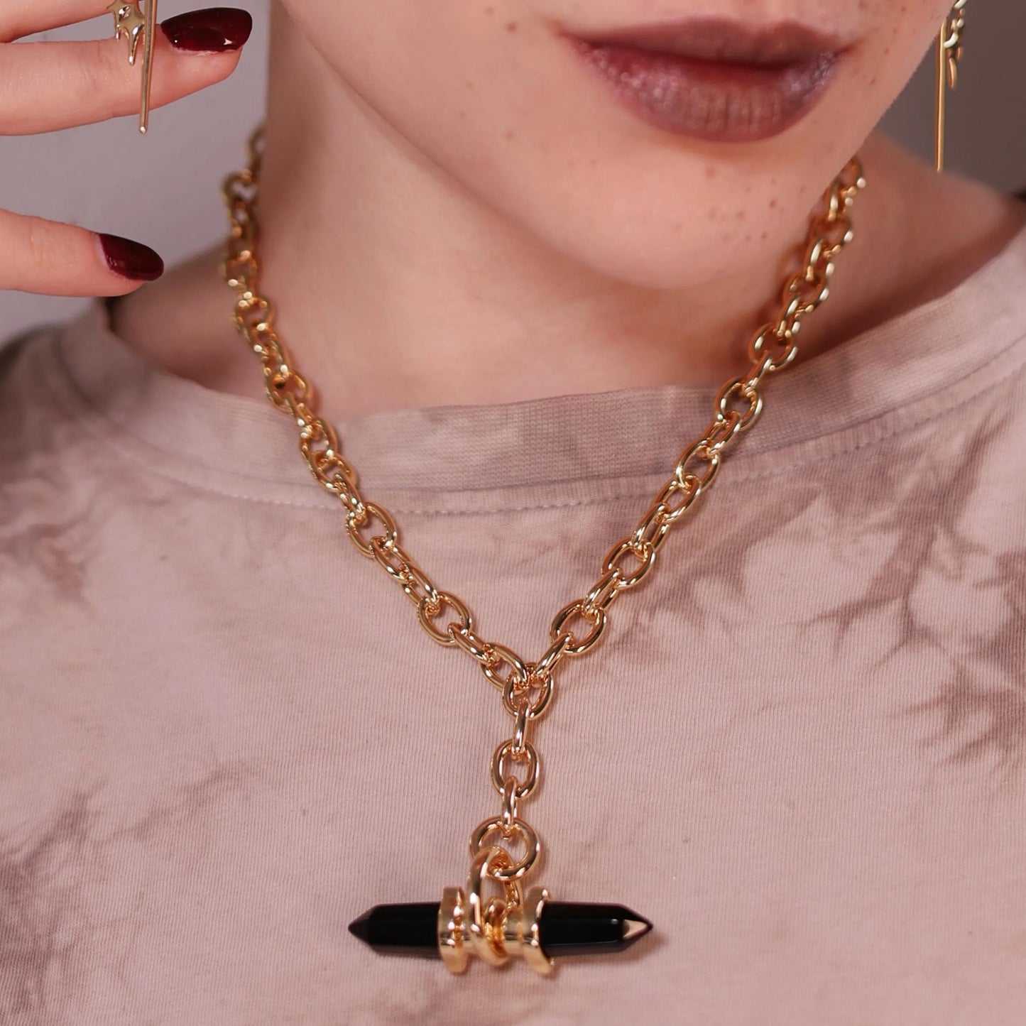 Model wearing the gold Dual Prism Necklace with a horizontal black crystal pendant, chunky chain, and structured gothic styling.