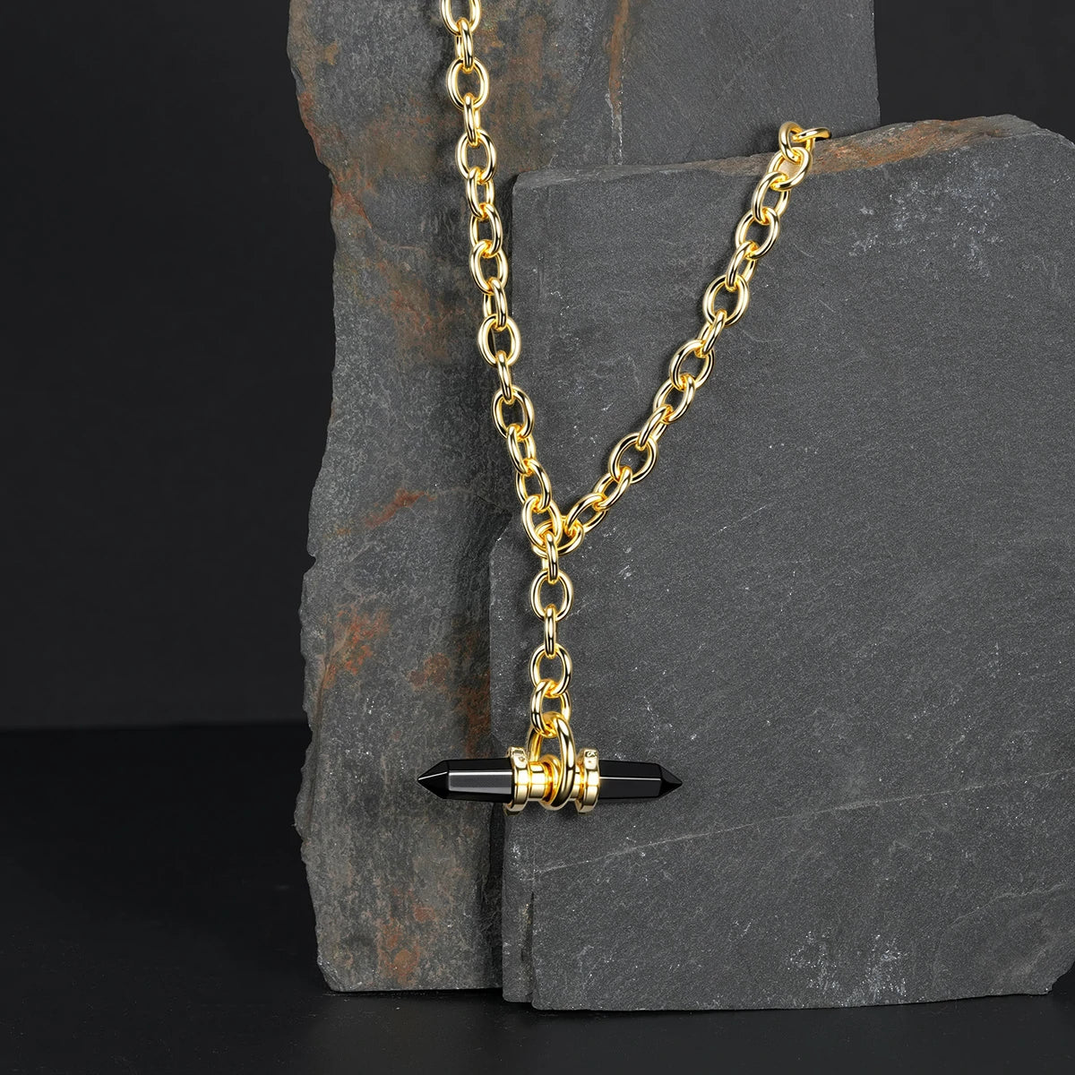 Gold Dual Prism necklace with black pendant displayed on dark stone