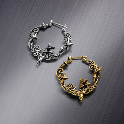 Silver-tone and gold-tone hoop earrings with mushroom and snail details, laid flat on a metallic surface