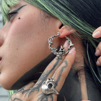 Model wears a silver-tone hoop earring with mushroom and vine details, shown in close-up profile view