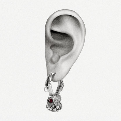 Silver-tone jackalope hoop earring with red gemstone eye worn on a model's earlobe, close-up view