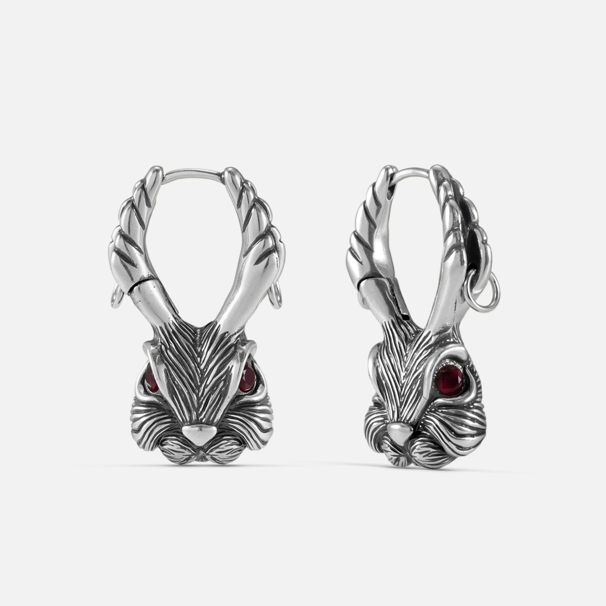 Pair of oxidized silver-tone jackalope hoop earrings with antlers and red gemstone eyes, front view