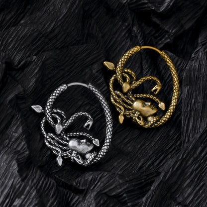 Silver and gold Enchanted Medusa hoop earrings displayed on black feathers