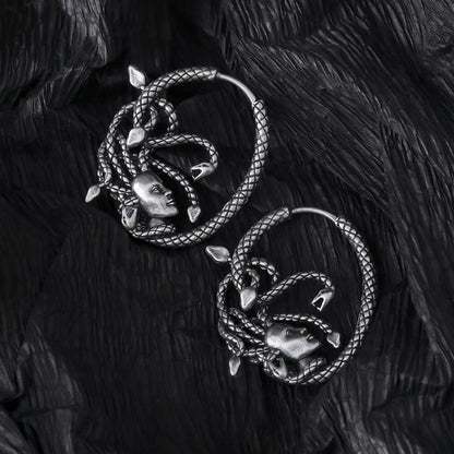 Pair of silver Enchanted Medusa hoop earrings displayed on black feathers