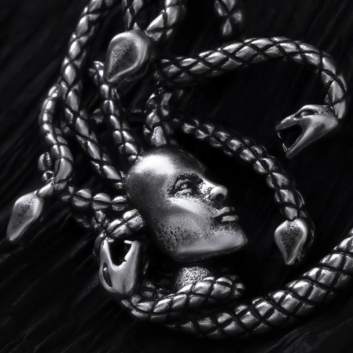 Close-up of silver Enchanted Medusa earring with face and serpent details