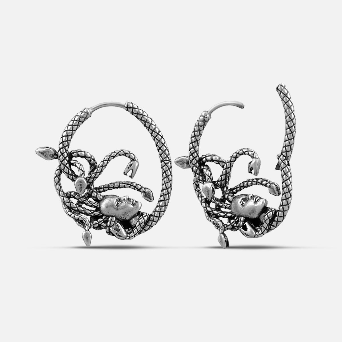 Pair of oxidized silver-tone hoop earrings with intertwined snake coils and a small face at the center, front and side view