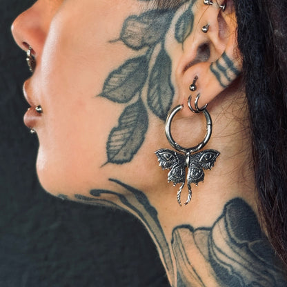 Moth charm hoop earring worn on a tattooed neck and ear, close side profile view