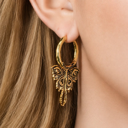 Gold-tone Enchanted Moth hoop earring worn on an earlobe, with detailed wings and a long curled tail