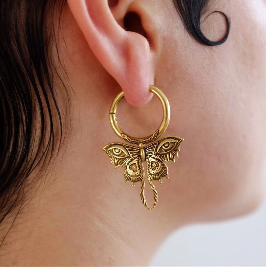 Close-up side view of a gold-tone Enchanted Moth hoop earring worn on the earlobe