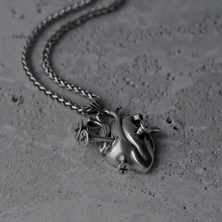 Silver Enduring Heart necklace shown coiled beside its anatomical heart pendant