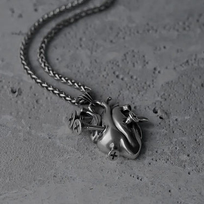 Silver Enduring Heart necklace shown coiled beside its anatomical heart pendant