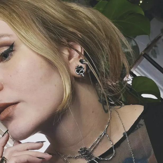 Close up of a blonde model wearing a coiled snake tunnel earring with layered necklace