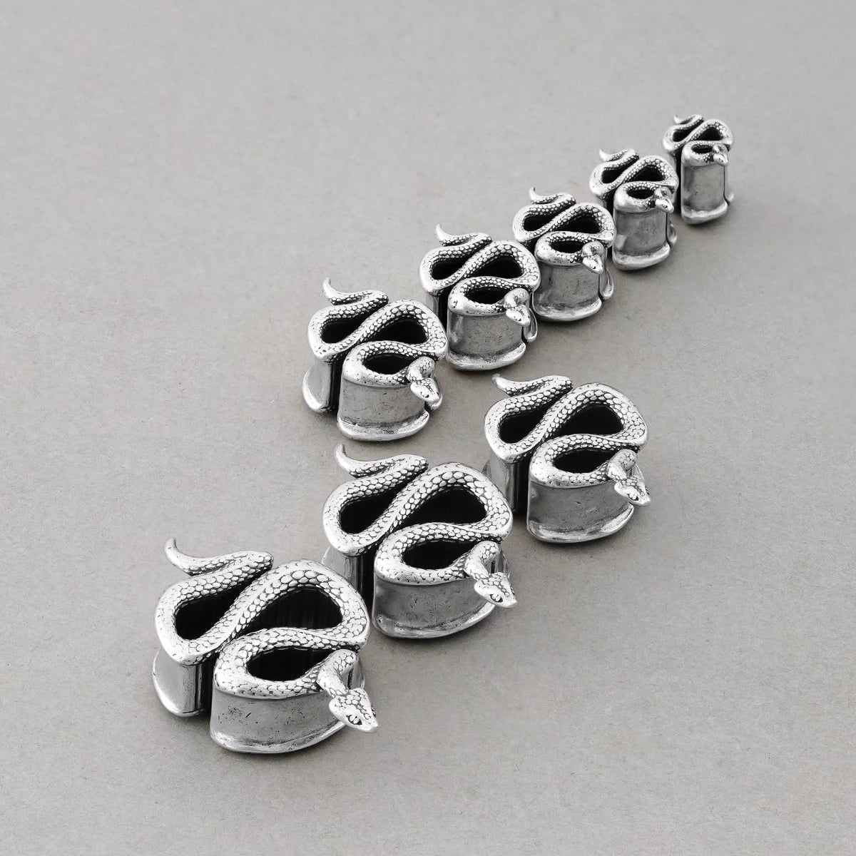 Enigmatic Serpent tunnels in graduated sizes arranged on a light surface