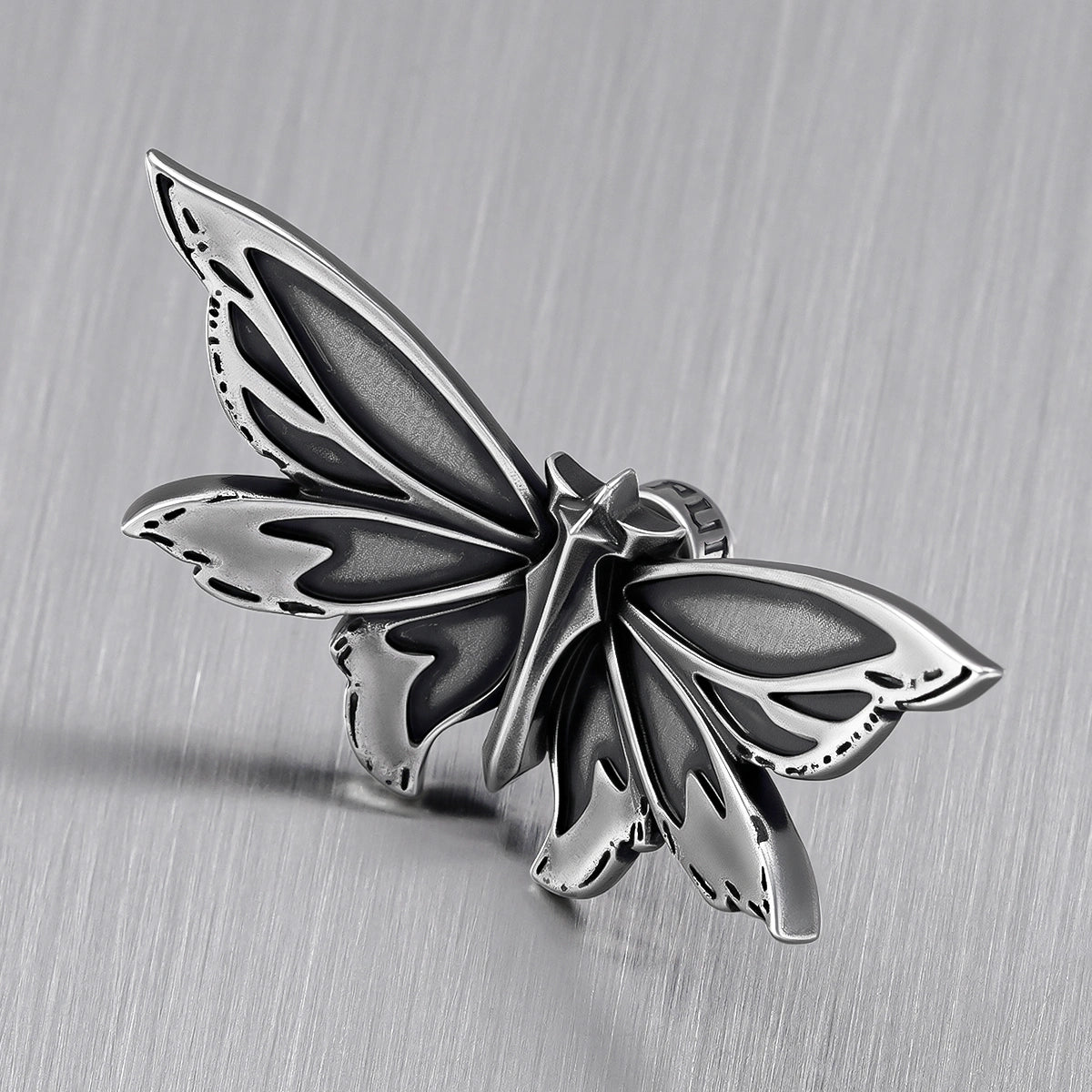 Close-up of silver Eternal Moth ear stud with layered wing details