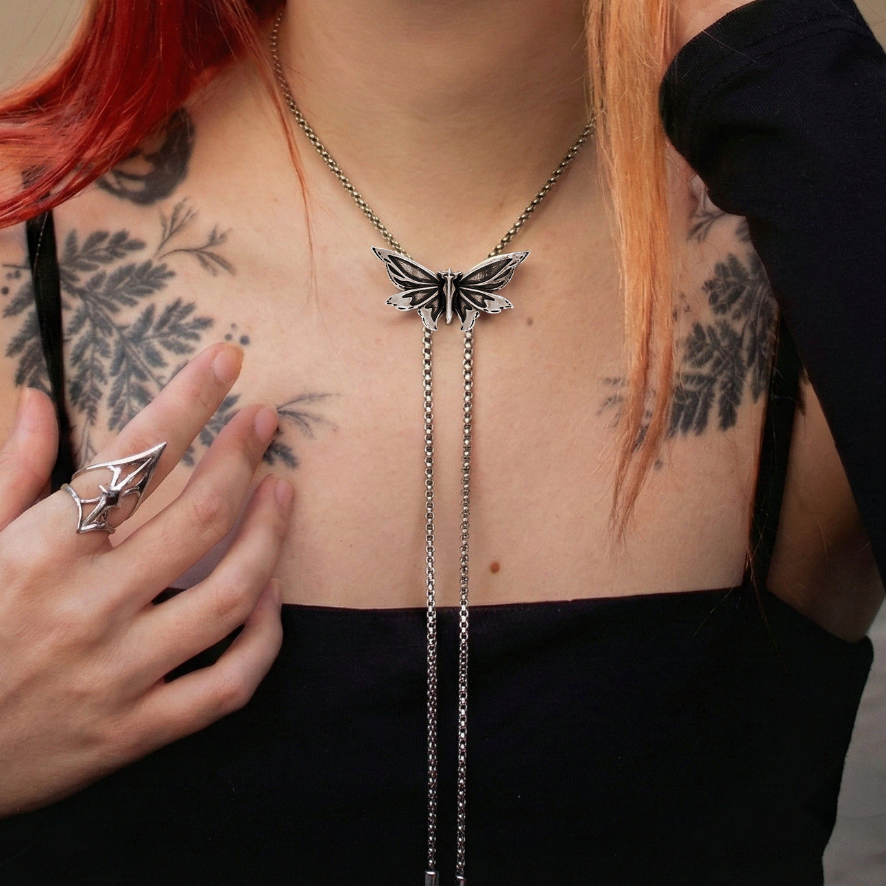 eternal moth necklace shown on a model, featuring sculpted moth wings and long chain drops in a front-facing styling shot