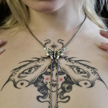 eternal moth necklace shown on a model, featuring sculpted moth wings and long chain drops in a close-up styling shot