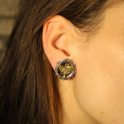 Model's ear detail showing a silver-tone tunnel with ornate scrollwork and gold-tone moth design worn in the lobe