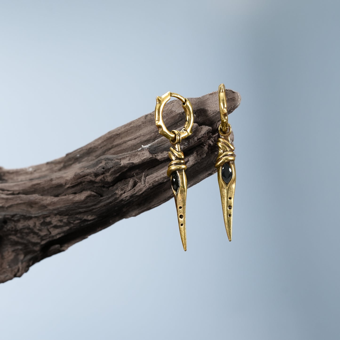 Gold Eye Dagger Earrings displayed on driftwood with sharp dagger drop details