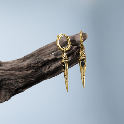 Gold Eye Dagger Earrings displayed on driftwood with sharp dagger drop details