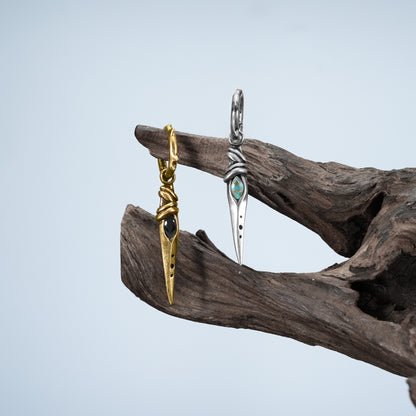Eye Dagger Earrings in silver and gold displayed on driftwood with gothic relic styling