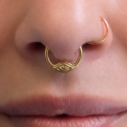 Gold-tone Eyelock Clicker worn as a septum ring, showing its minimal eye-inspired design.