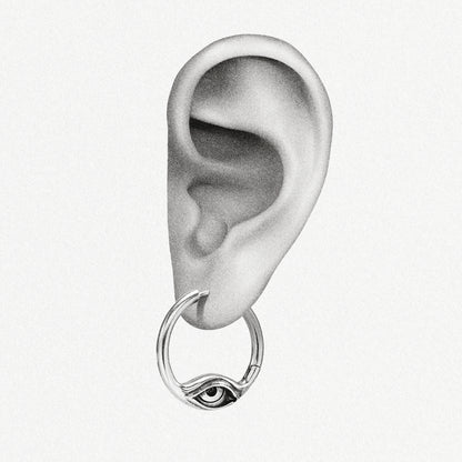 Illustration of a silver-tone hoop earring with an eye design hanging from a drawn ear
