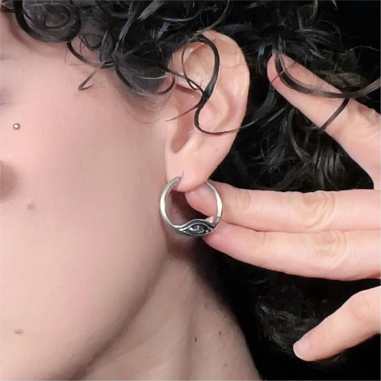 Model wearing silver Eyelock Earrings with abstract eye motif and sleek hoop design