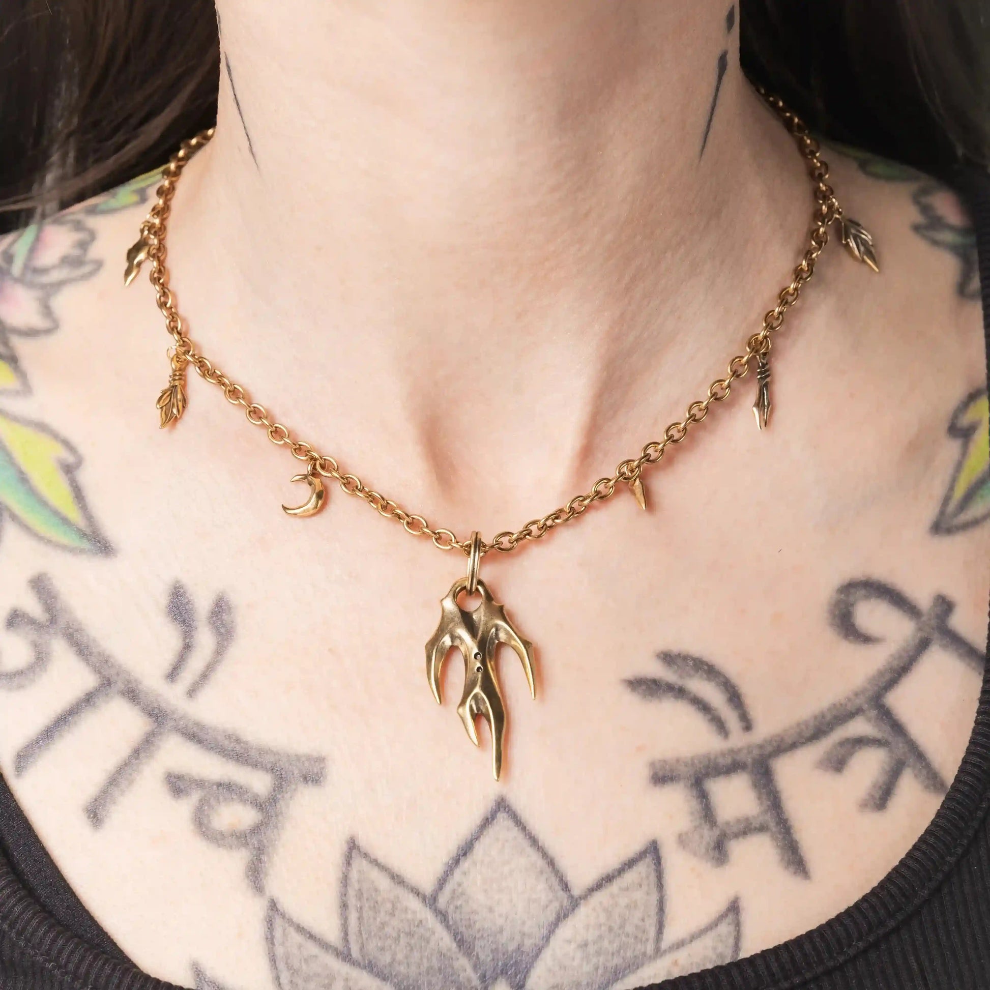 Model wearing the gold Feral Husk Necklace with tooth and leaf charms