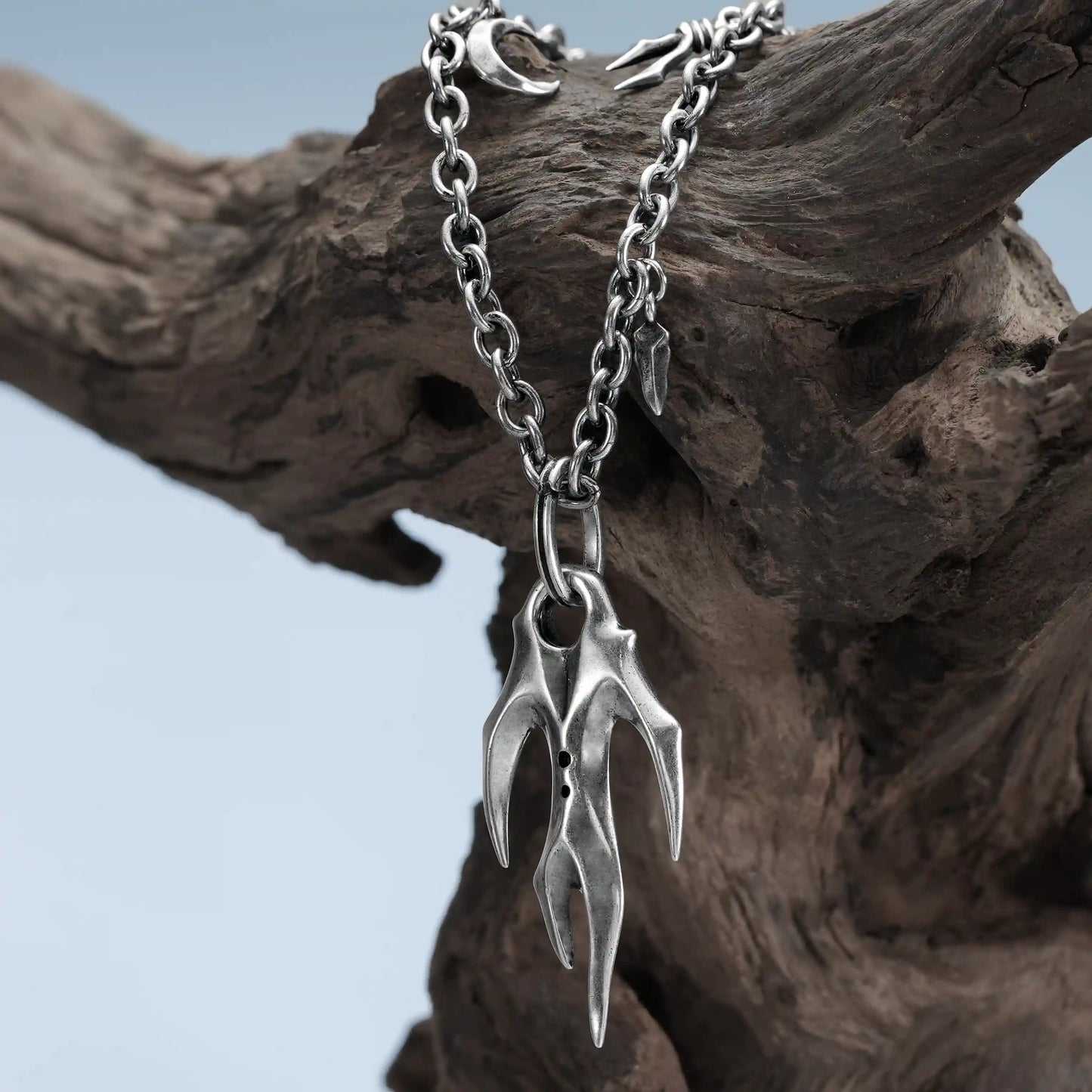 Silver Feral Husk Necklace hanging on weathered wood with dark forest inspired design