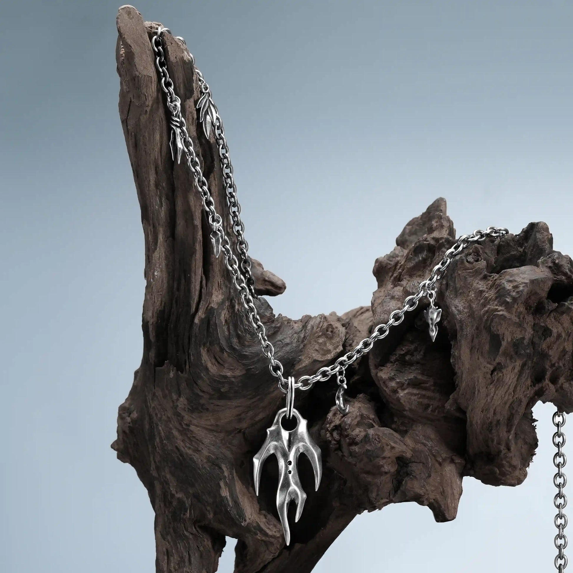 Antiqued silver Feral Husk Necklace styled on driftwood with claw pendant detail