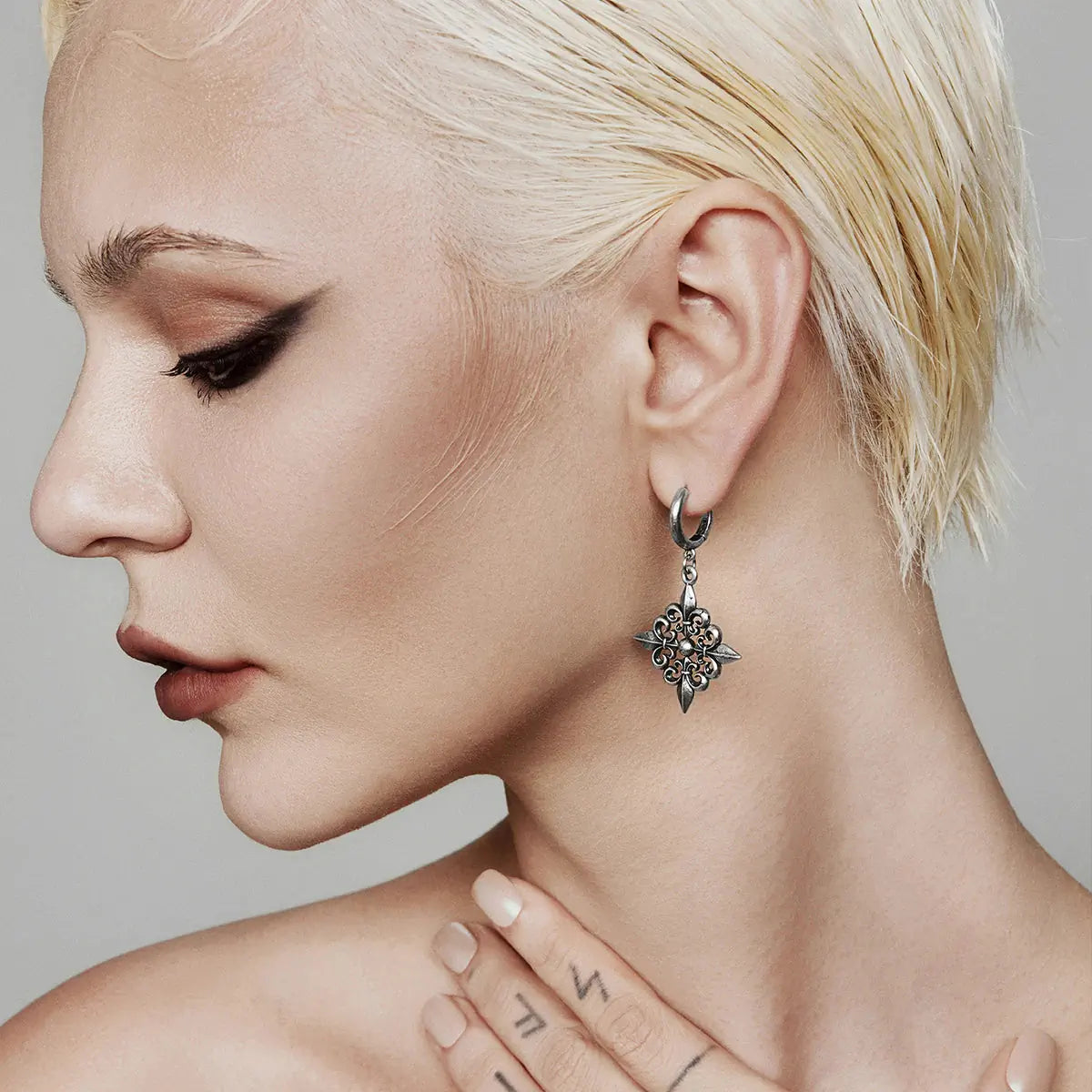 Fleur-de-Lis Elegance Earrings in 925 sterling silver, worn in a clean side portrait with a short platinum-blonde crop and ba