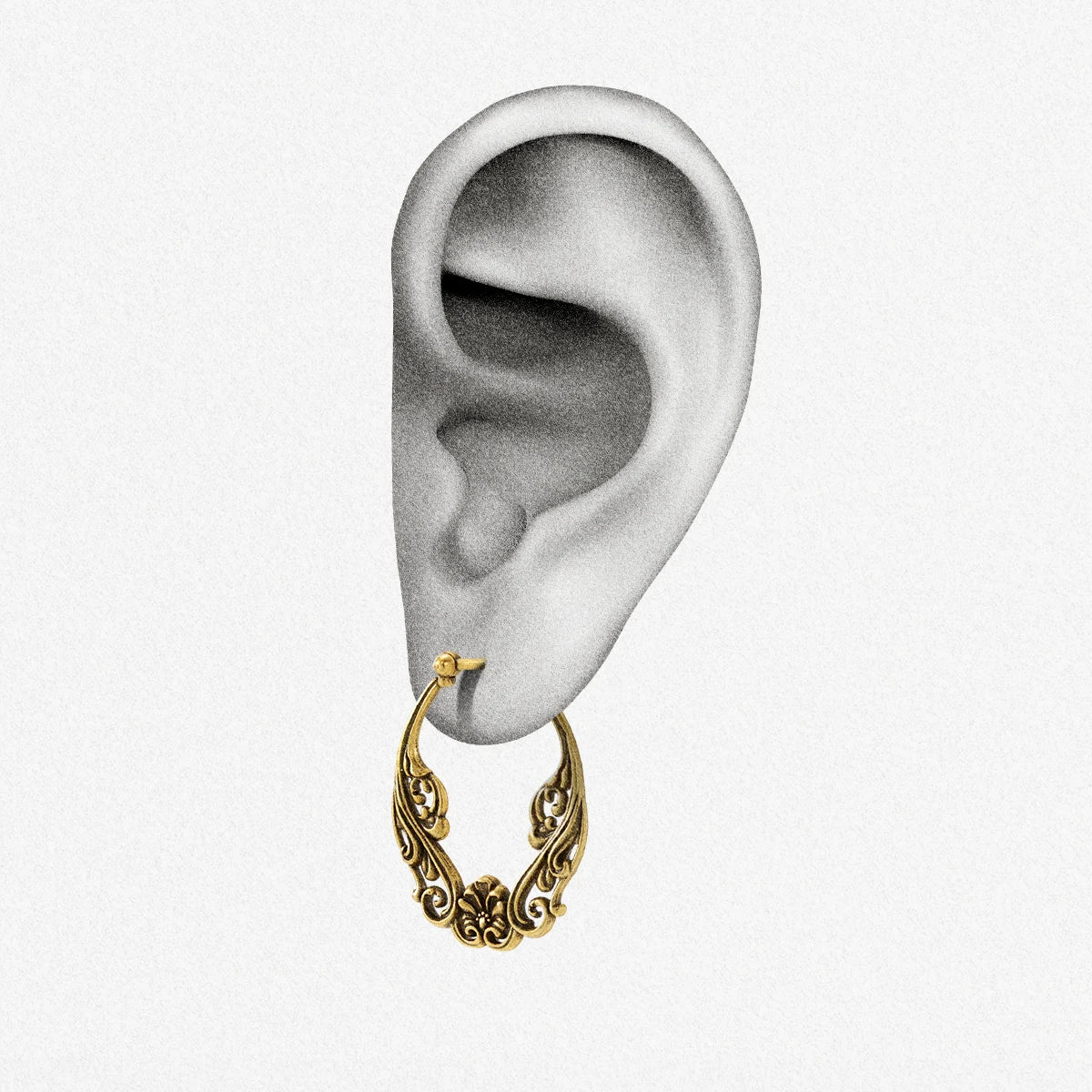 Close-up of an ear wearing a gold-tone floral scroll hoop earring with latch closure