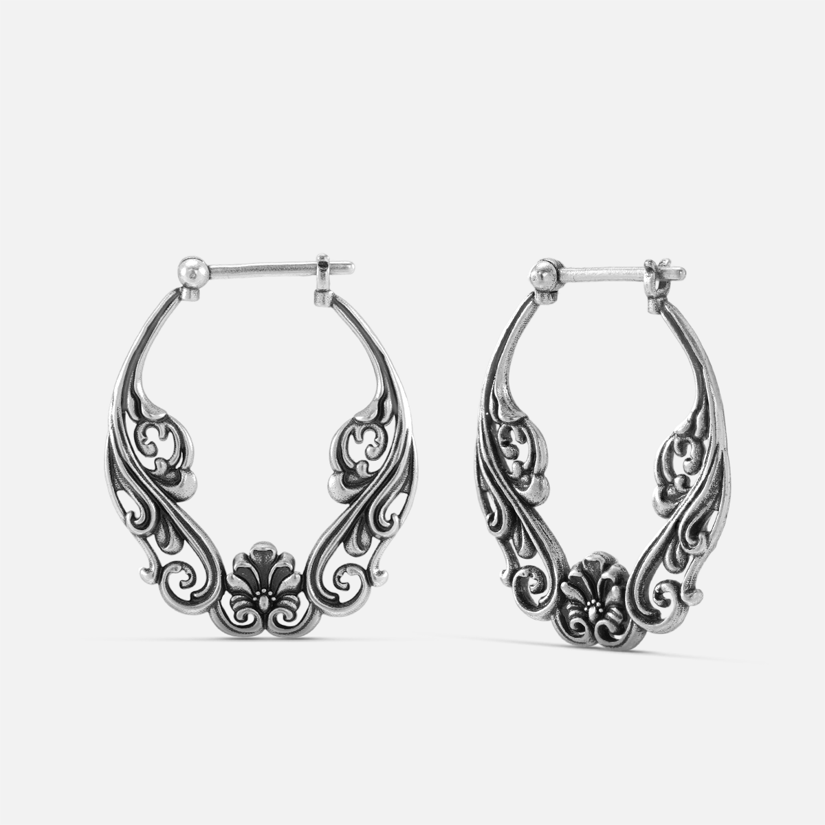 Pair of oxidized silver-tone hoop earrings with floral scroll filigree design, front view