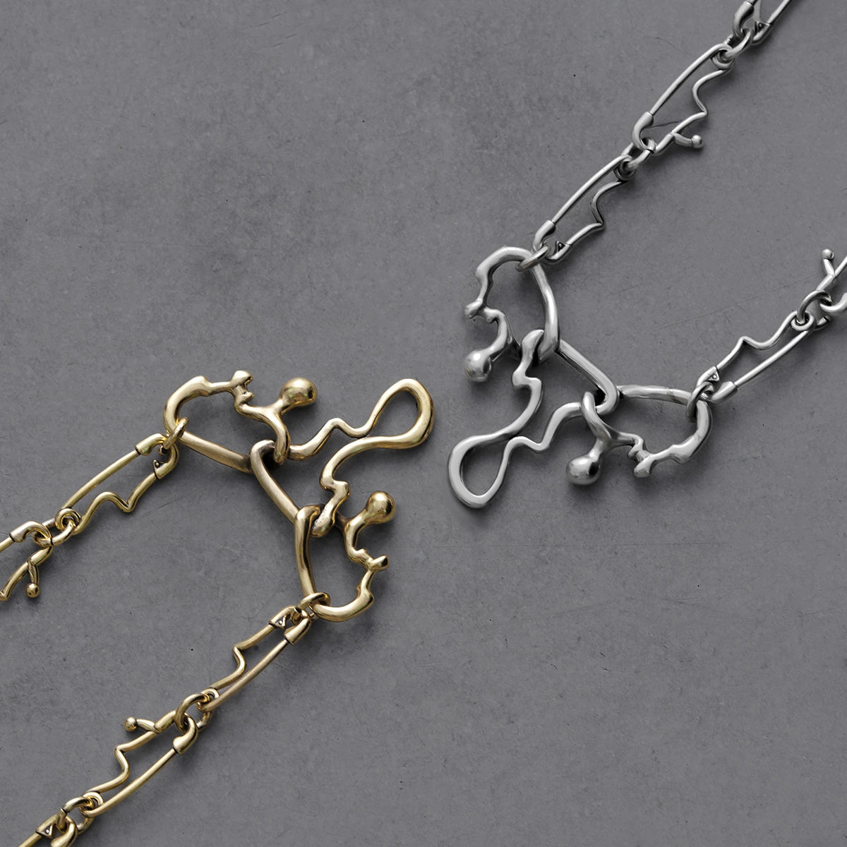 Silver and gold Fluid Pin necklaces with abstract melting chain links