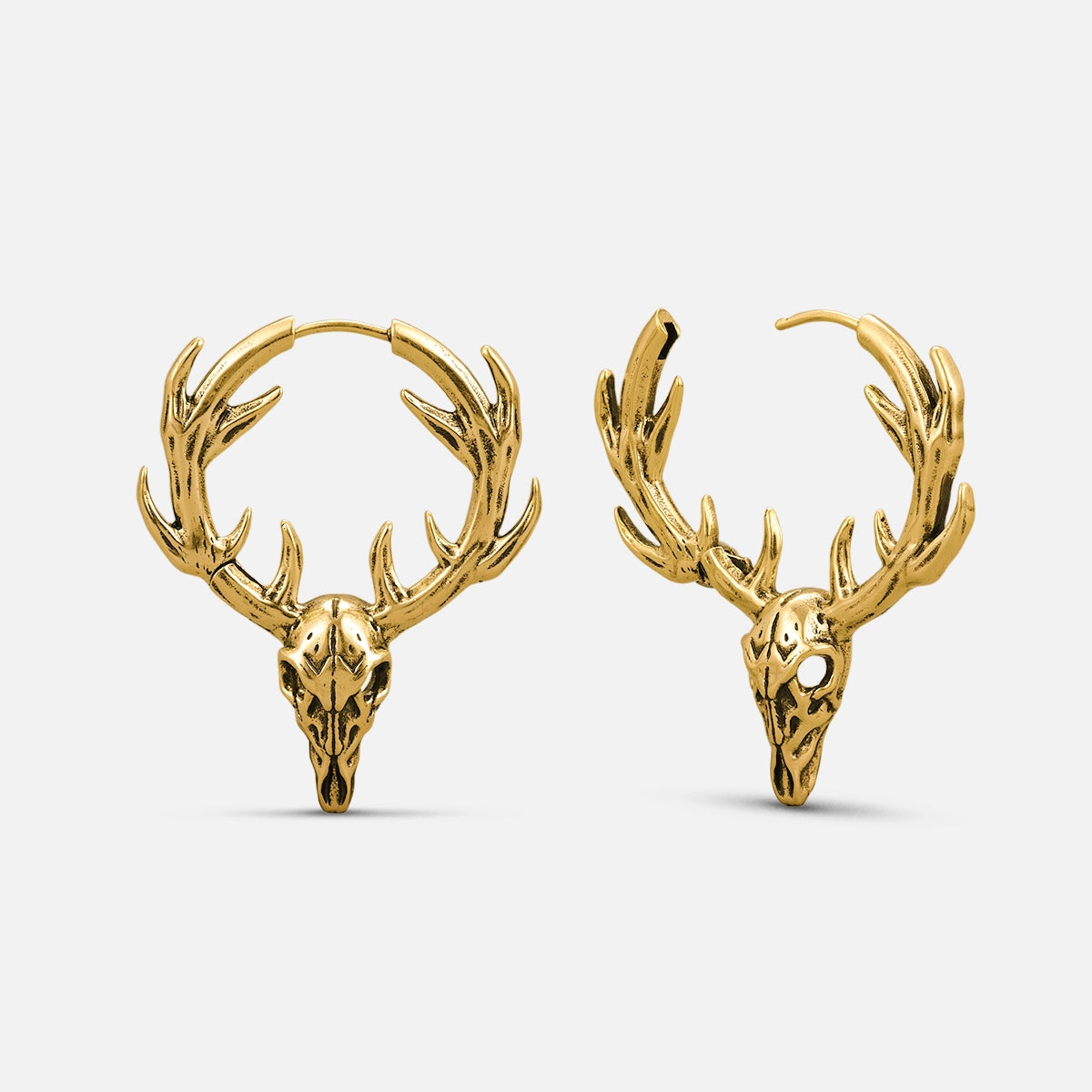 Pair of gold-tone stag skull hoop earrings with antlers displayed side by side against a plain background