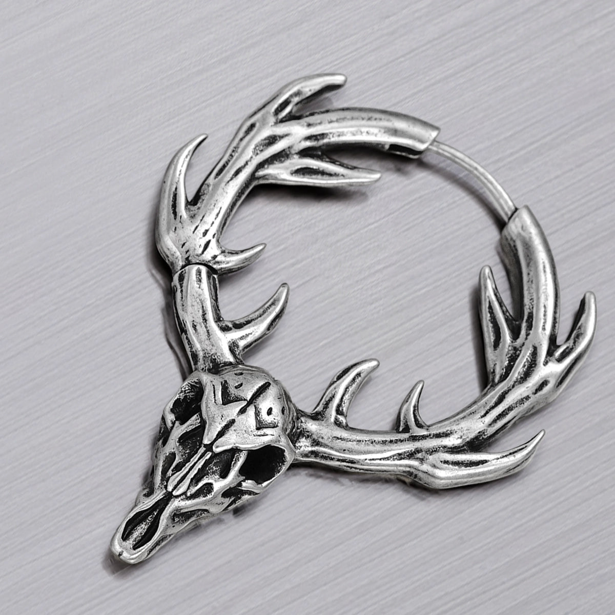 Close-up of silver Forest Stag hoop earring with antlered skull detail