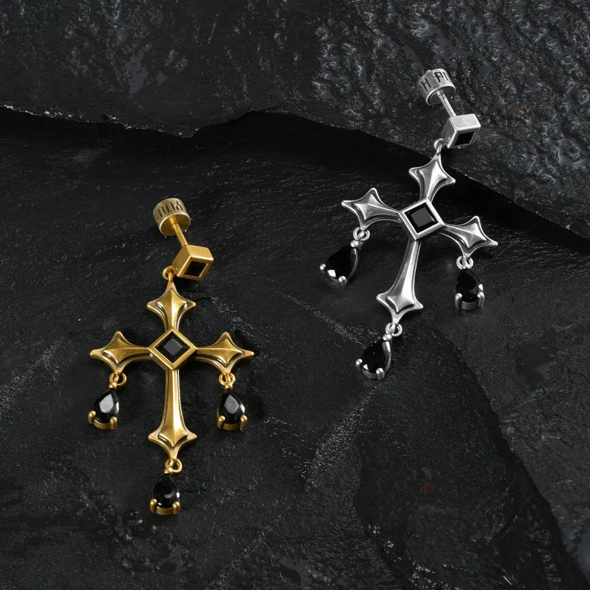 Silver and gold Forsaken Vow Earrings arranged together on black textured fabric.
