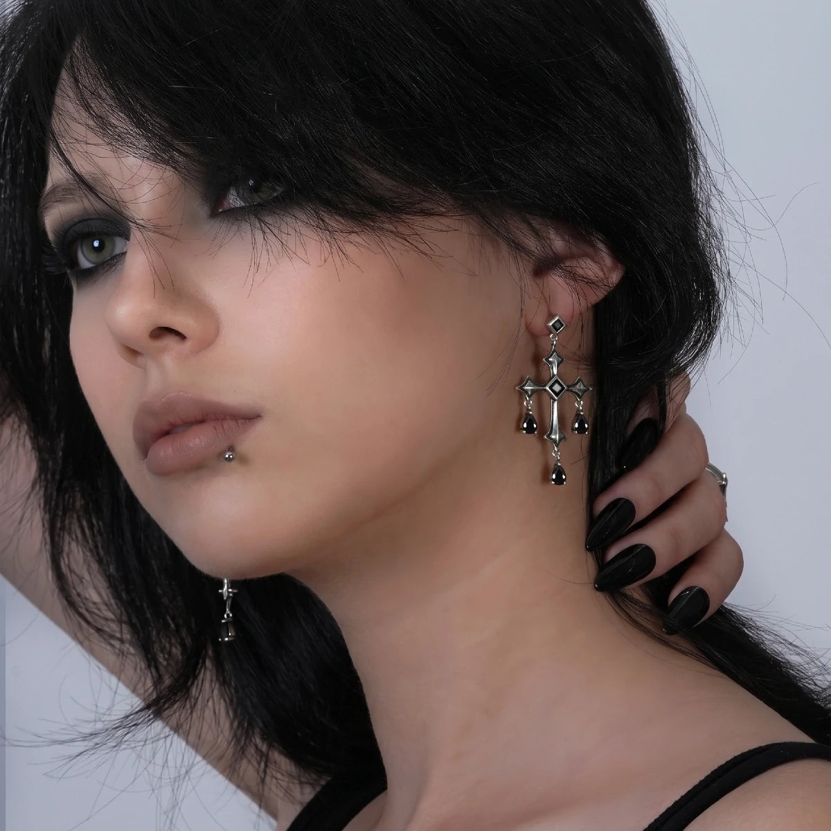 Forsaken Vow Earrings in antiqued silver worn on the ear in a side-profile portrait with dark bobbed hair.