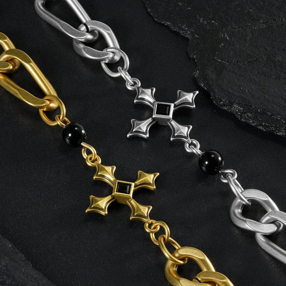Silver and gold Fractured Creed Bracelet links shown in a close diagonal arrangement on black textured fabric.