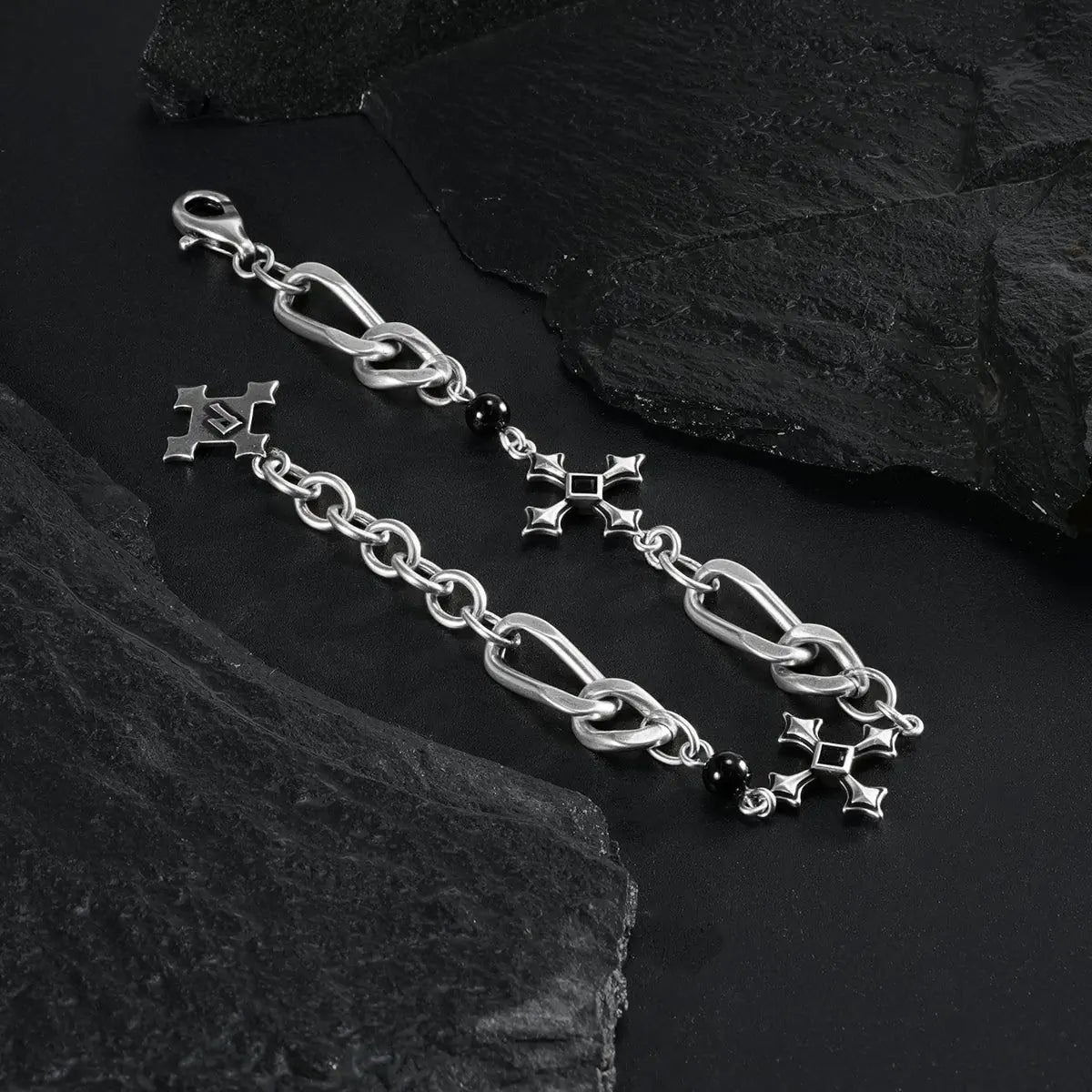 Silver Fractured Creed Bracelet arranged in a loop on black textured fabric.