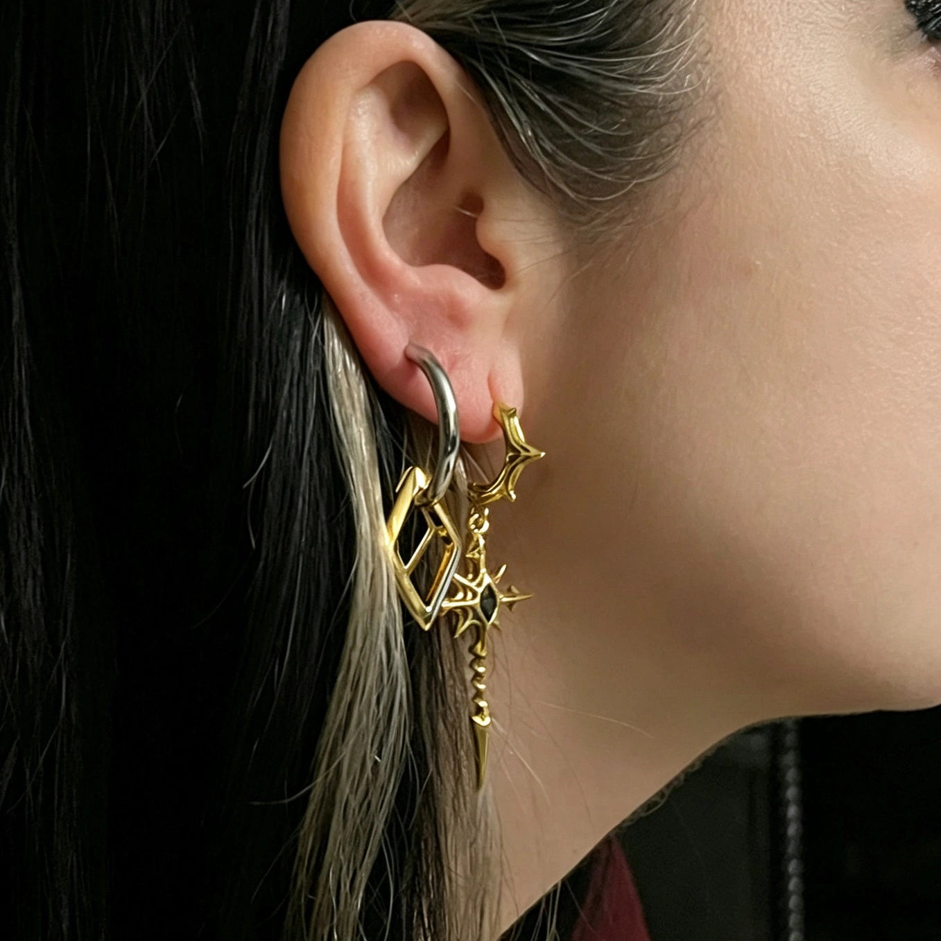 geometric duo earrings shown in a model close-up view, featuring silver hoop earrings with mixed geometric gold drops worn on the ear