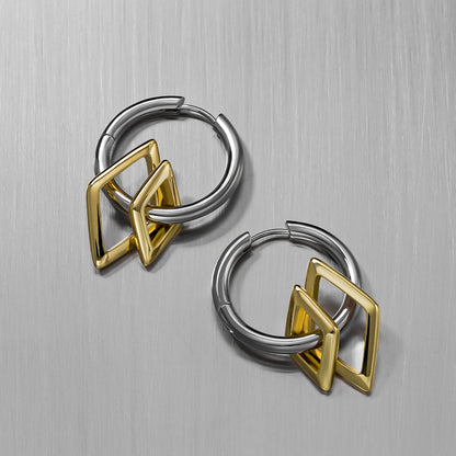 Two silver-tone hoop earrings with gold-tone geometric charms, angled view on a brushed metal surface