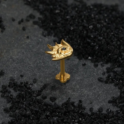 Gold sea creature conch ear stud with black stone center on dark background