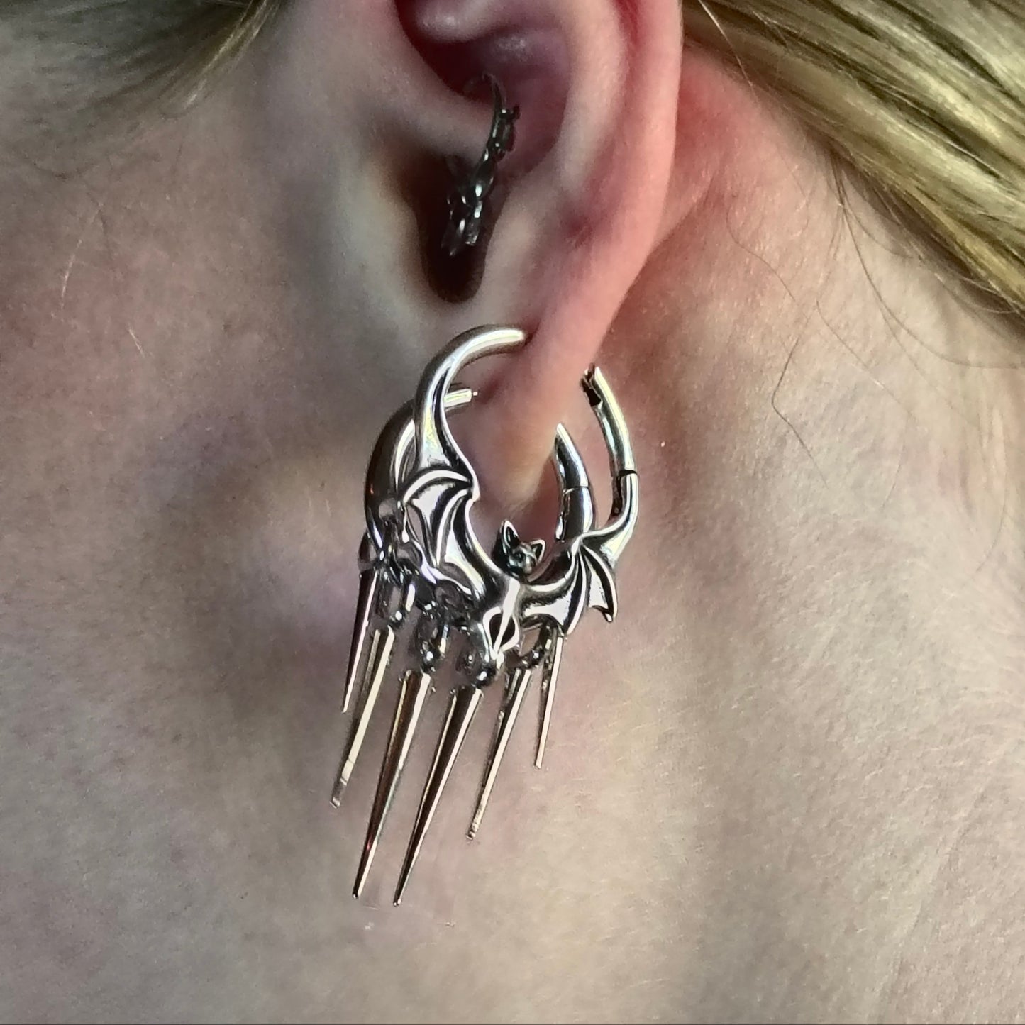 Close-up of silver Gothic Bat hoop earring with long pointed drops