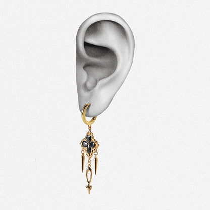 Gold-tone hoop earring with black crystal cross pendant and spike details on an ear illustration