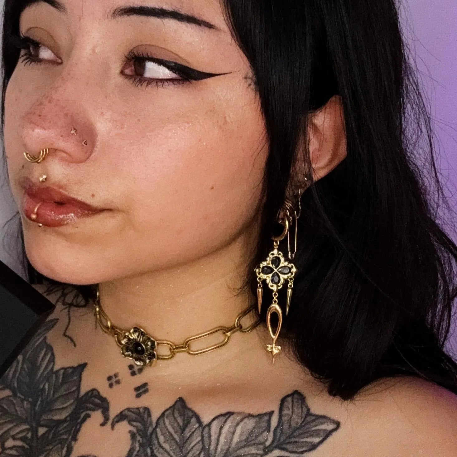 Model wearing the gold Gothic Bloom Earrings with dark floral stone cluster, dangling spike details, and bold gothic styling.
