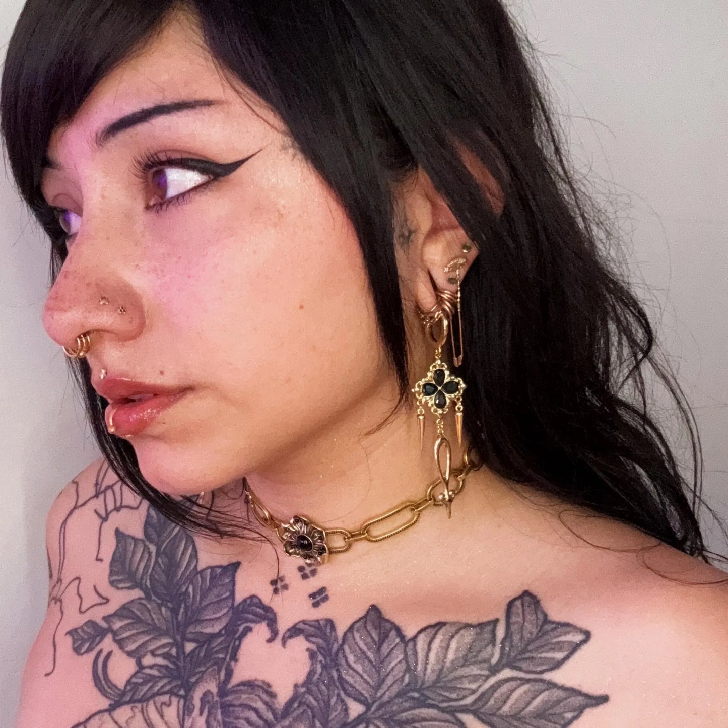 Side view of a model wearing the gold Gothic Bloom Earrings, showing the dark floral cluster, long spike charms, and gothic drop silhouette.